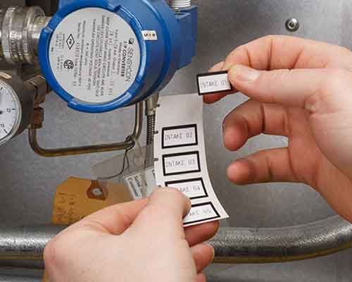 Een persoon die met de M610 geprinte labels op een machine aanbrengt.