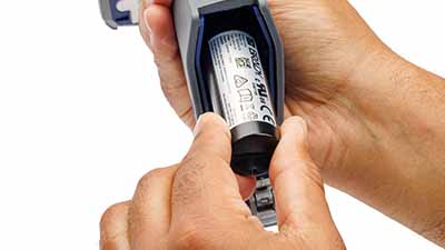 Een persoon die een batterij in de pistoolgreep van de lezer steekt.