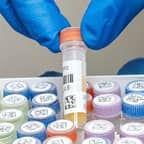 Een laborant houdt een testbuisje met twee barcodelabels vast.