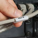 Een persoon met een wikkellabel om een grijze kabel gewikkeld.