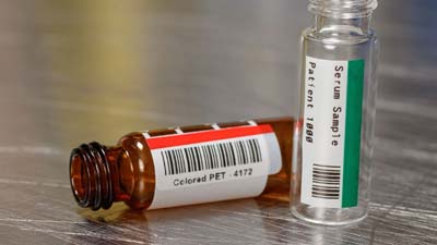 Twee flesjes met een rood en groen polyesterlabel.