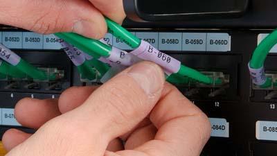 Een zelflaminerend vinyl wikkellabel wordt om een groene Cat-5e-kabel gewikkeld.