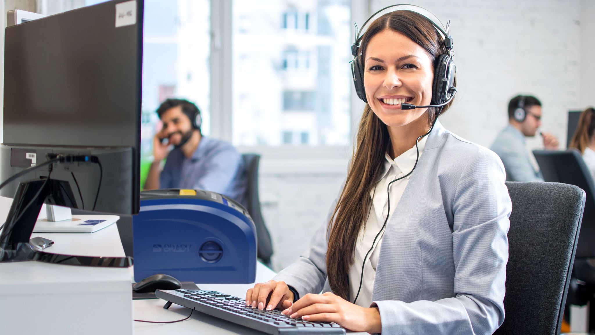 Een persoon die een telefoon vasthoudt. Het telefoonscherm toont een felgeel label dat is gemaakt met Express Labels Mobile. In de achtergrond staat een plastic bakje met het geprinte label erop.